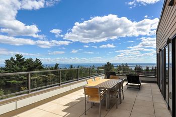 a patio with a table and chairs on a balcony overlooking the ocean at Bluestone Lofts, Duluth, MN 55803